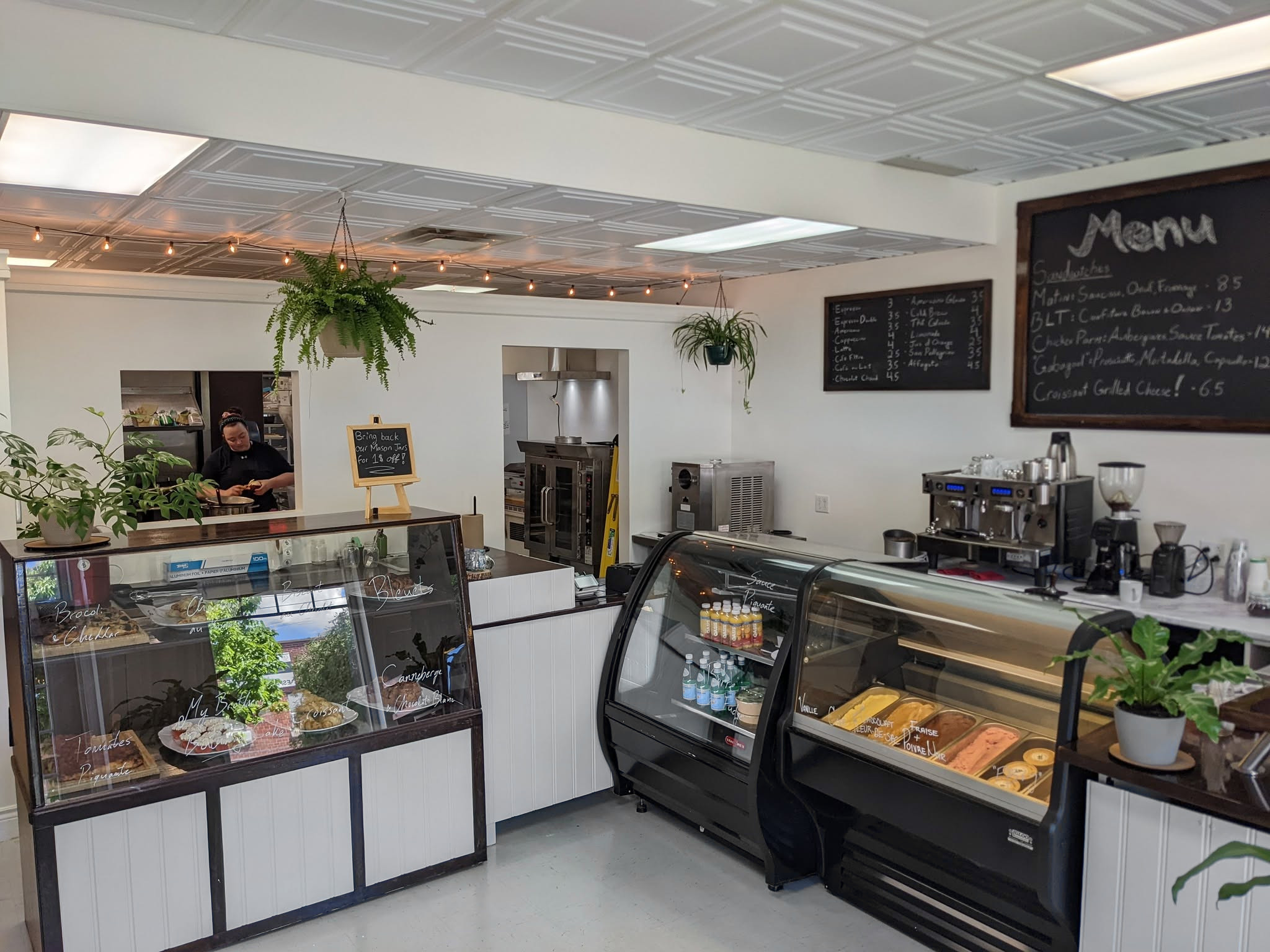 Inside Café Greenwood: the white counter, two pastry cases, the espresso machine and the chalkboard menu on the wall